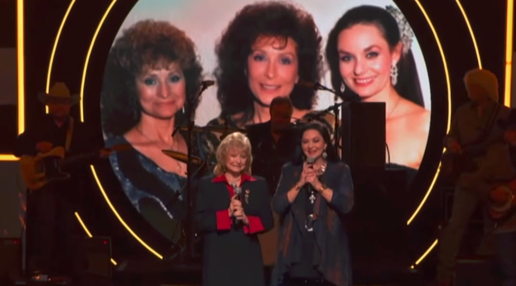 Loretta Lynn’s Sisters, Crystal Gayle & Peggy Sue Wright, Pay Tribute To Her With Sweet Performance Of “Coal Miner’s Daughter”